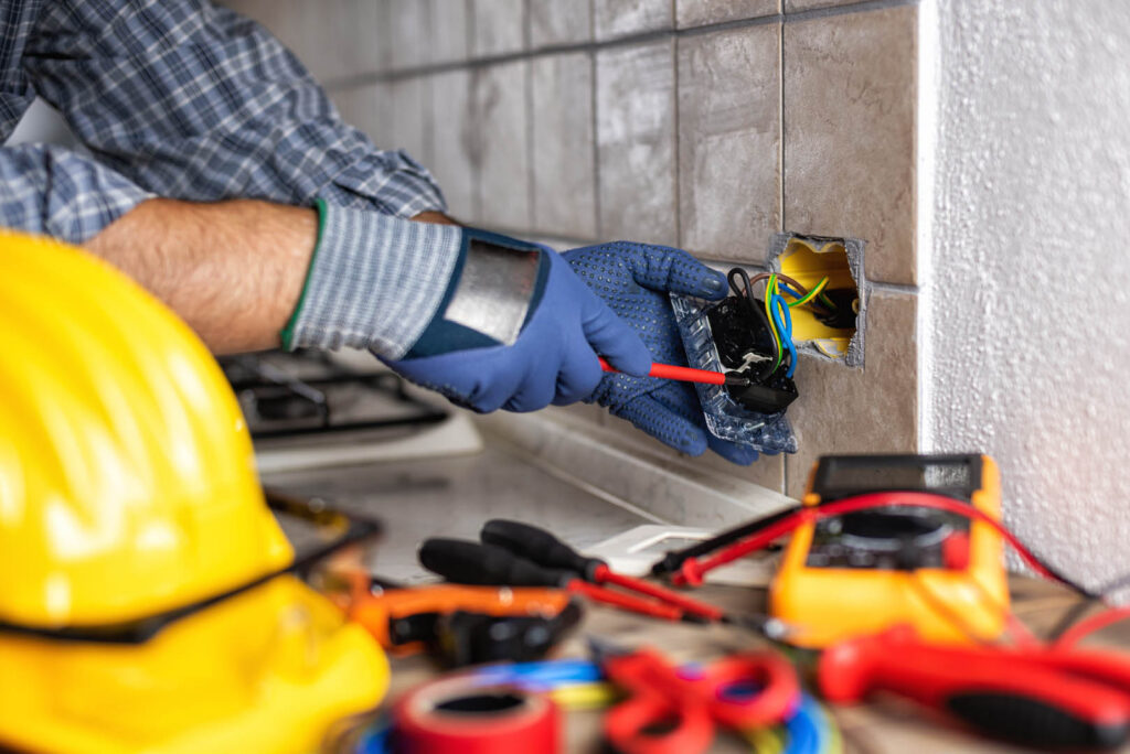 Electrician at work with screwdriver fixes the cable in the sockets of a residential electrical system. Construction industry.